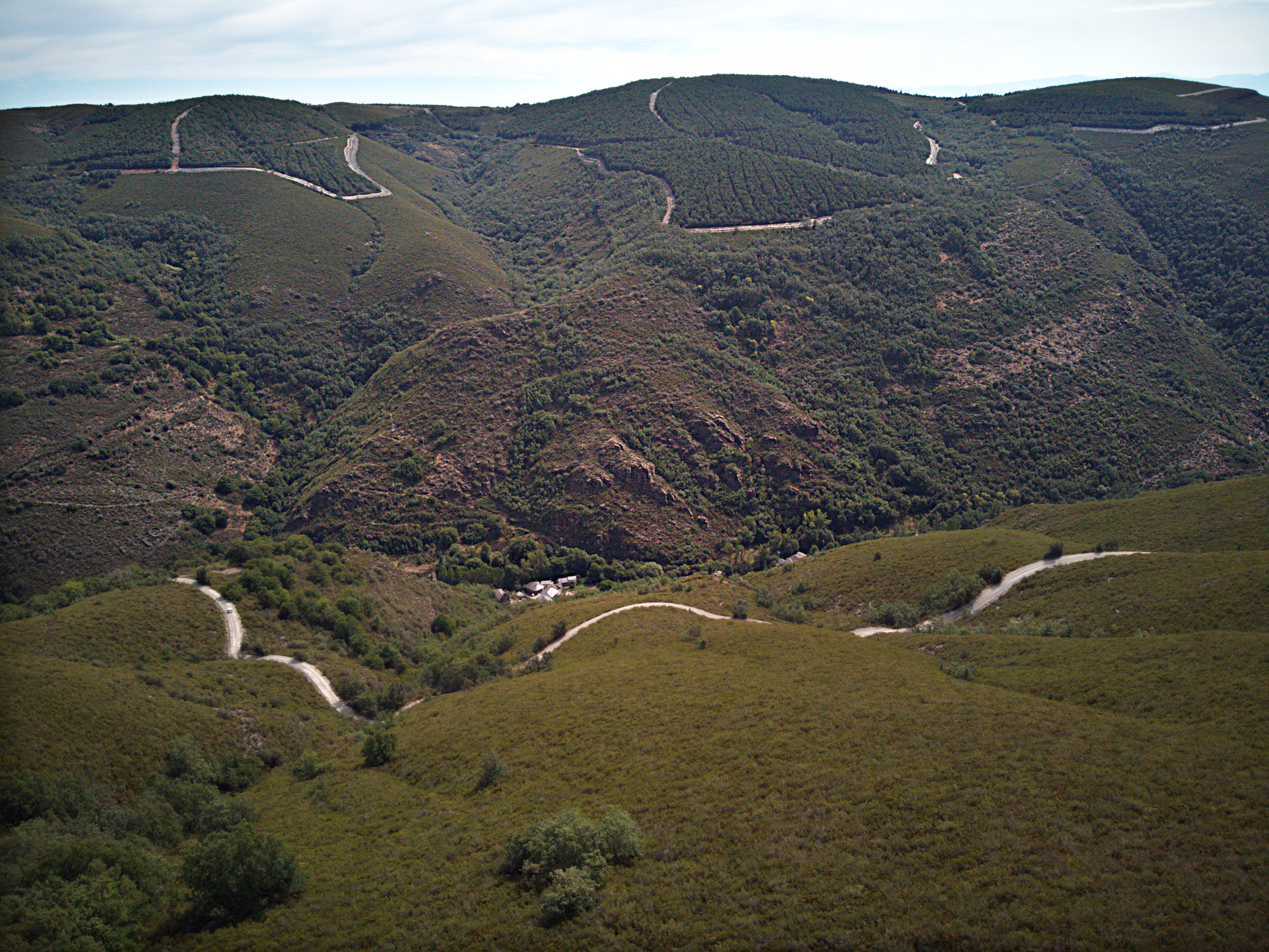 Camino sinuoso por las laderas y casas de Aira da Pedra al fondo del valle. Fotografía: Pepe Couceiro · Lugares con Alma.