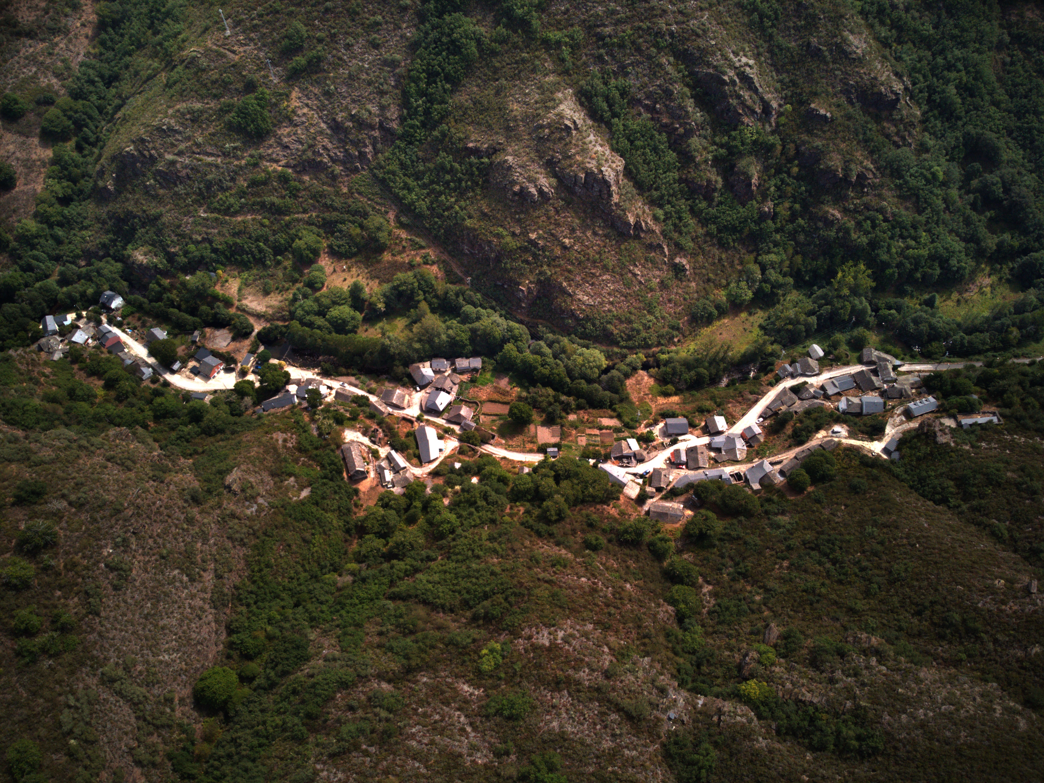 Vista aérea de las casas y caminos de Aira da Pedra rodeados de monte. Fotografía: Pepe Couceiro · Lugares con Alma.