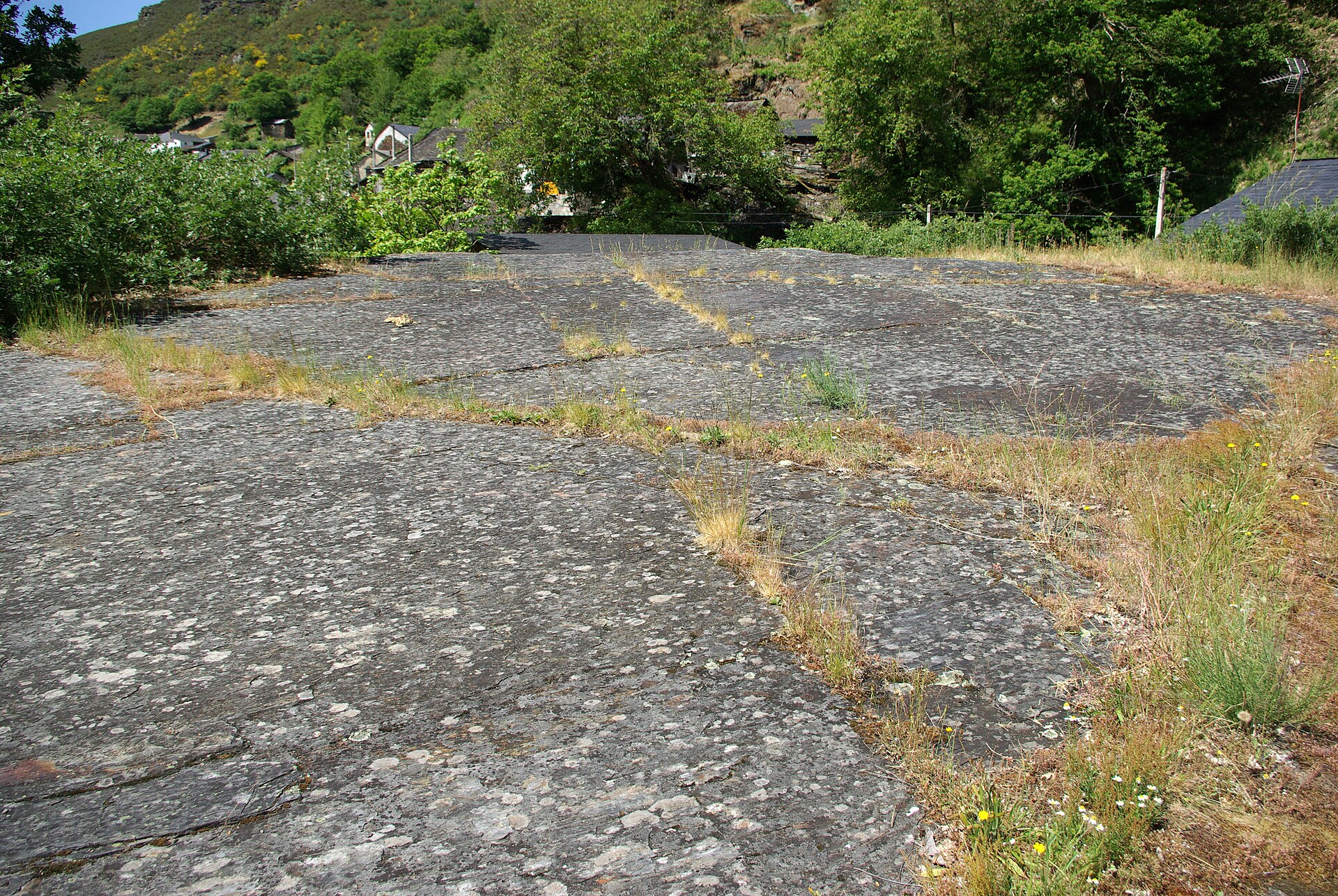 Gran era de piedra de Aira da Pedra rodeada por casas y vegetación. Fotografía: David Pérez (DPC), Wikimedia Commons, CC BY 3.0.